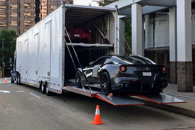 A car being loaded into a professional multi-vehicle enclosed carrier